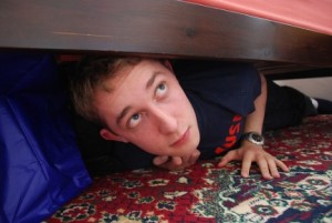 man hiding under bed